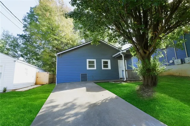 a brick house with a big yard plants and large trees