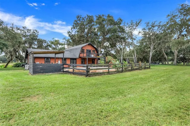a view of a house with a big yard and large trees