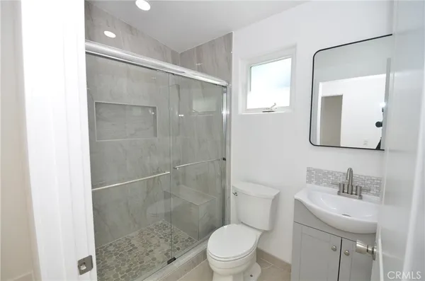 a bathroom with a shower sink vanity mirror and toilet