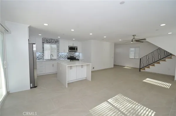 a view of open kitchen with white cabinets and stainless steel appliances