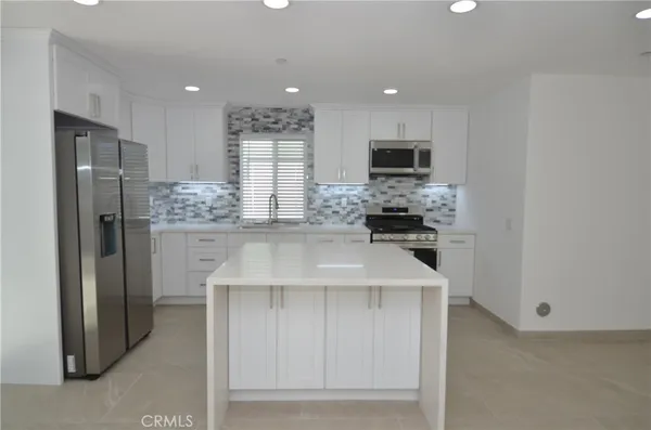 a kitchen with kitchen island white cabinets and stainless steel appliances