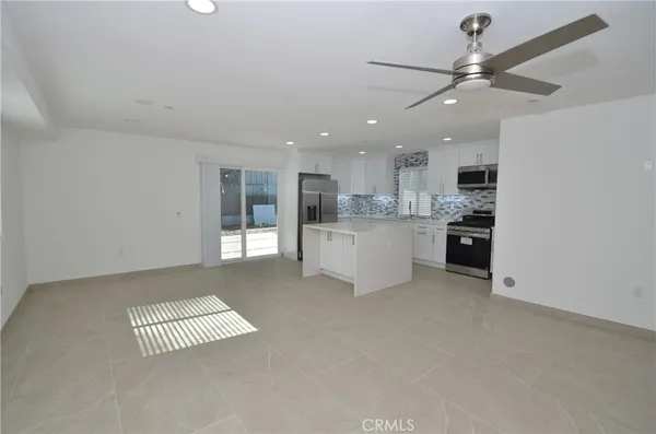a open kitchen with a refrigerator a stove top oven and white cabinets