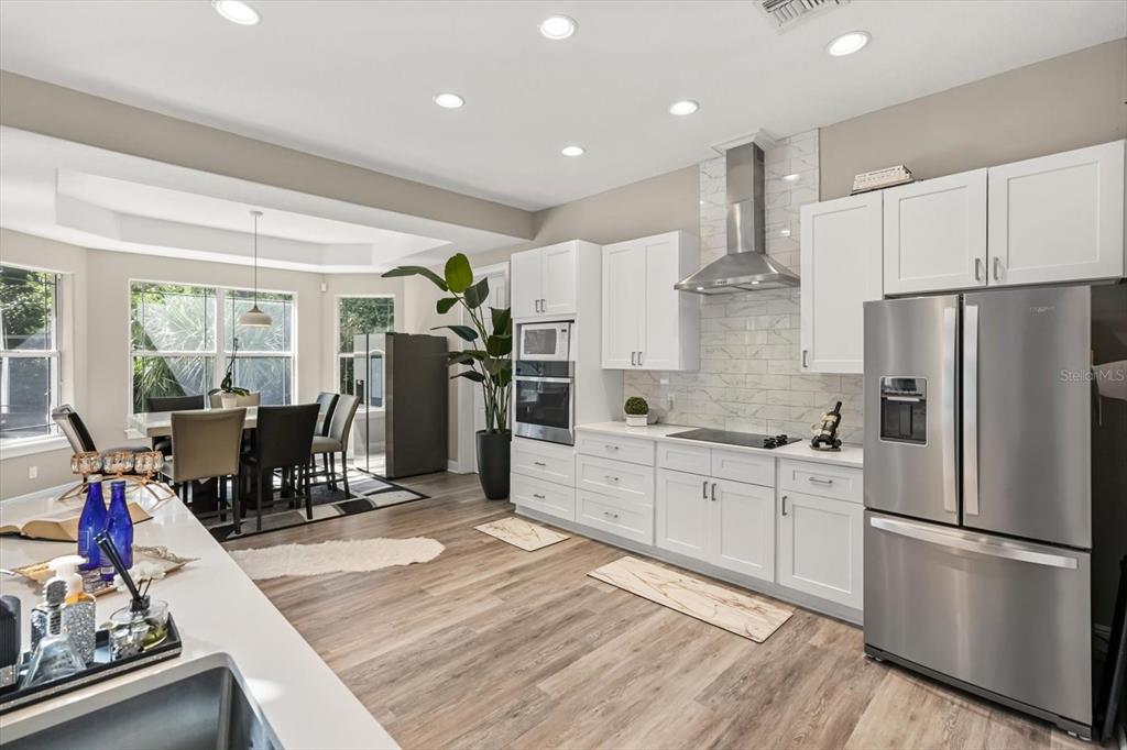 10370 Trout Road Orlando, FL 32836 - Photo 11 of 41 a kitchen with a refrigerator a stove top oven a sink dishwasher and white cabinets with wooden floor
