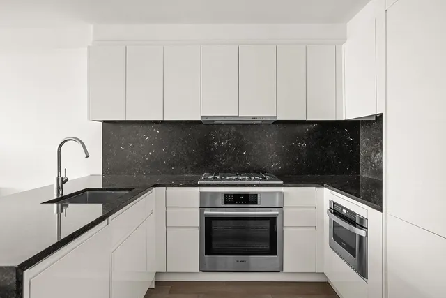 a kitchen with stainless steel appliances granite countertop a sink a microwave a refrigerator and white cabinets