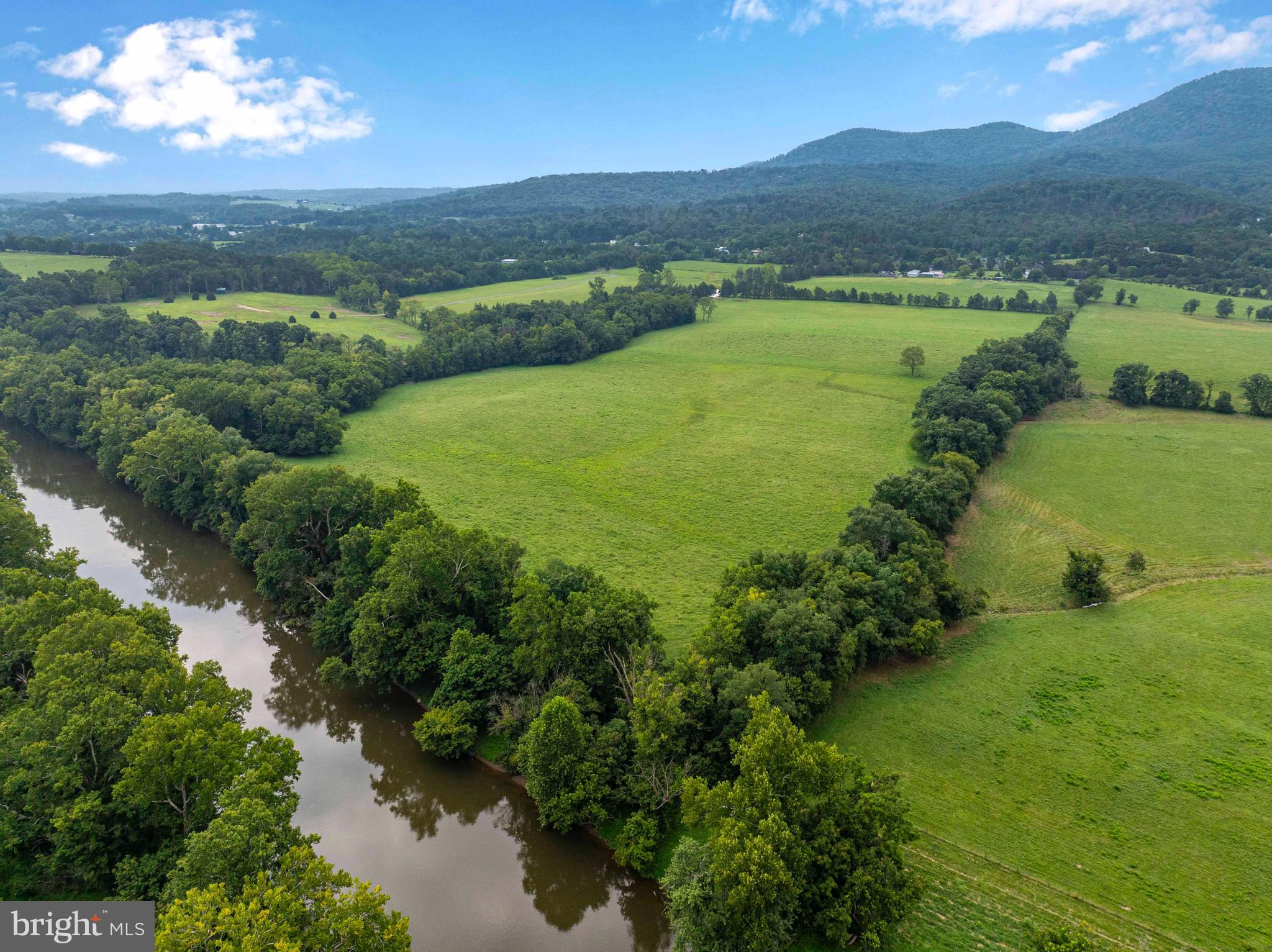 an aerial view of green landscape with trees houses and mountain view
