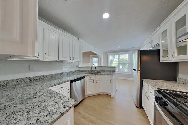 a kitchen with granite countertop a sink dishwasher stove and refrigerator