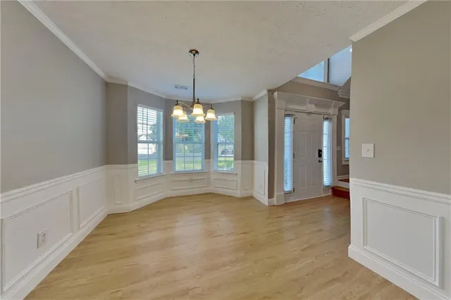a view of an empty room with window and chandelier fan