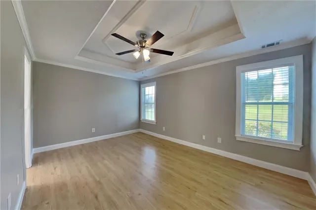 an empty room with wooden floor fan and windows