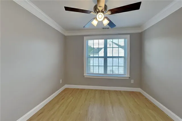 an empty room with a chandelier fan and windows