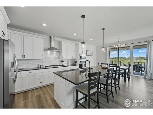 a kitchen with stainless steel appliances granite countertop a table chairs stove and white cabinets