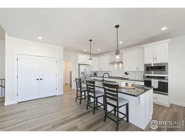 a kitchen with stainless steel appliances kitchen island granite countertop a table chairs and white cabinets