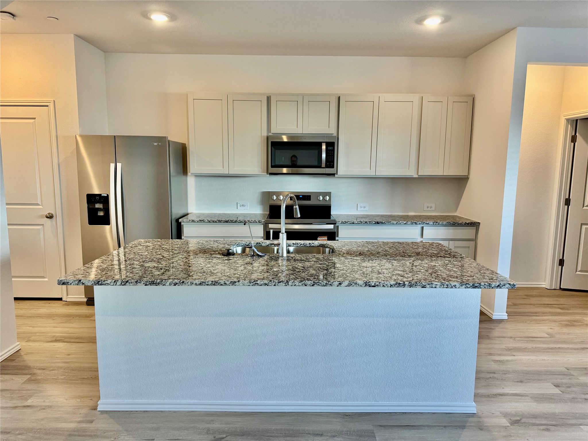 105 Calcite Road, Unit 4 Kyle, TX 78640 - Photo 2 of 7 Kitchen featuring light stone countertops, stainless steel appliances, a kitchen island with sink, light wood-type flooring, and gray cabinets