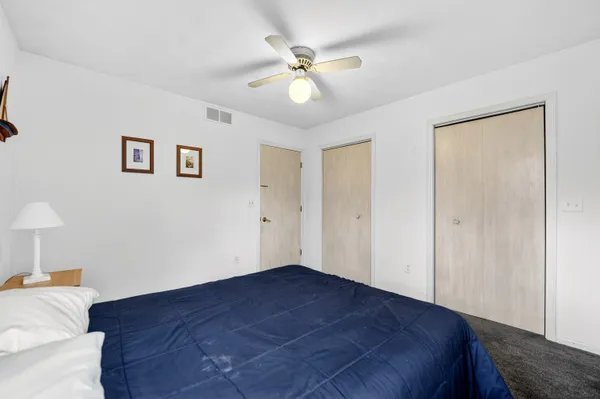 a bedroom with a bed a chair and a potted plant on a table