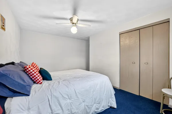 a bedroom with a bed dresser and a chandelier fan