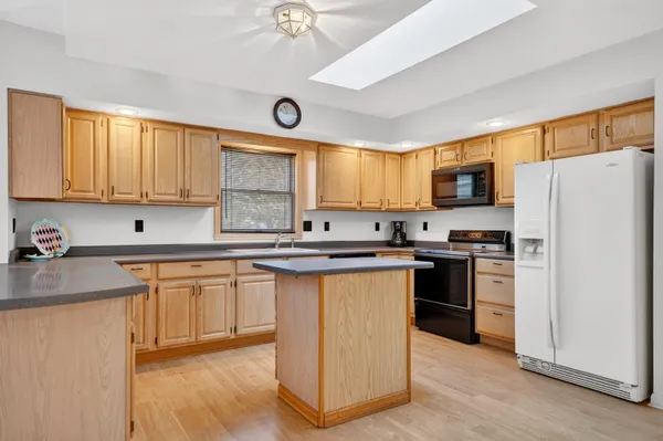 a kitchen with stainless steel appliances granite countertop a stove a sink dishwasher a refrigerator and a microwave oven with wooden floor