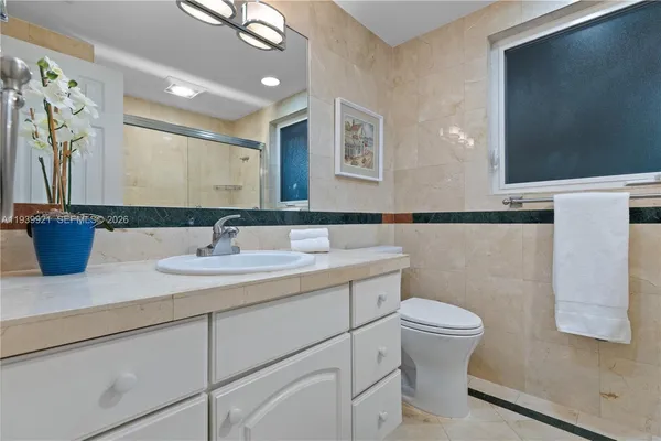 a bathroom with a granite countertop sink a toilet and a mirror