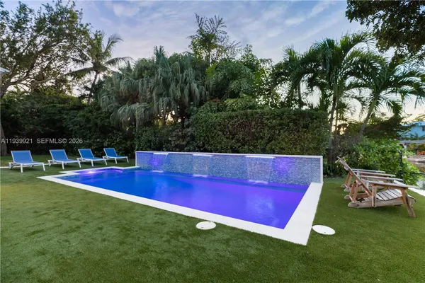a view of swimming pool with lawn chairs and plants