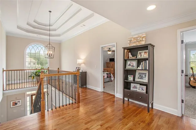a view of a hallway with wooden floor and a chandelier