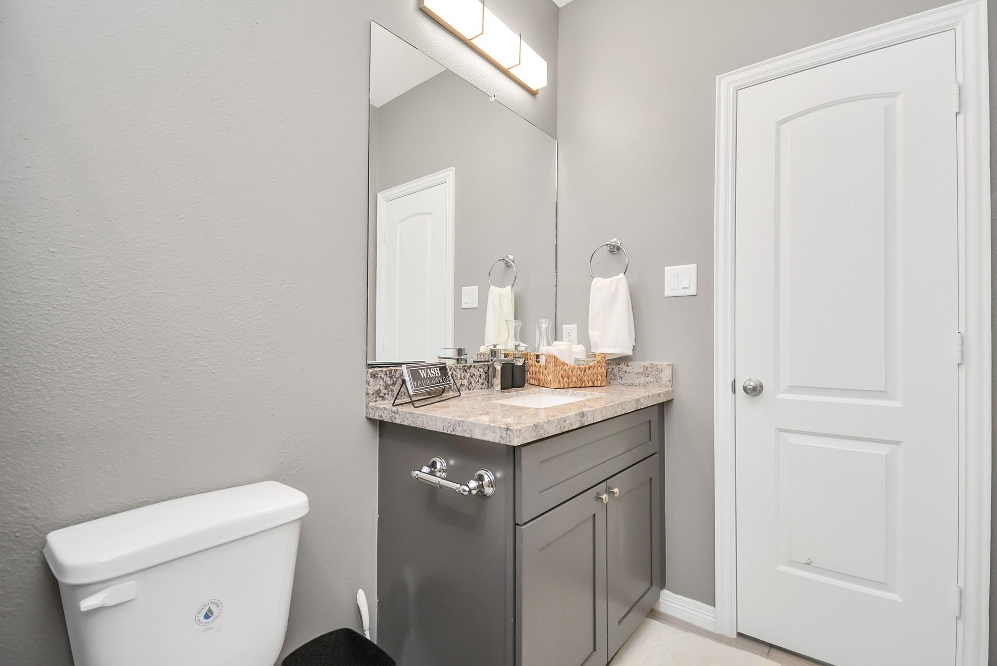 3019 Elysian Street Houston, TX 77009 - Photo 26 of 33 a bathroom with a granite countertop sink a toilet and a mirror