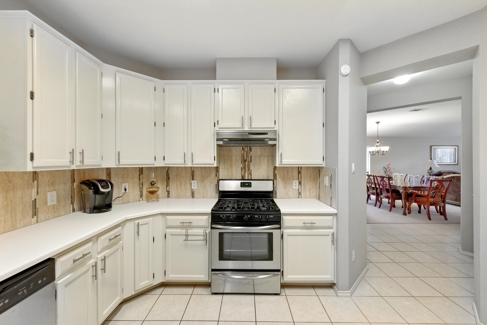 9602 Tea Rose Trail Austin, TX 78748 - Photo 14 of 27 Kitchen with stainless steel appliances, white cabinets, light countertops, backsplash, and light tile patterned floors