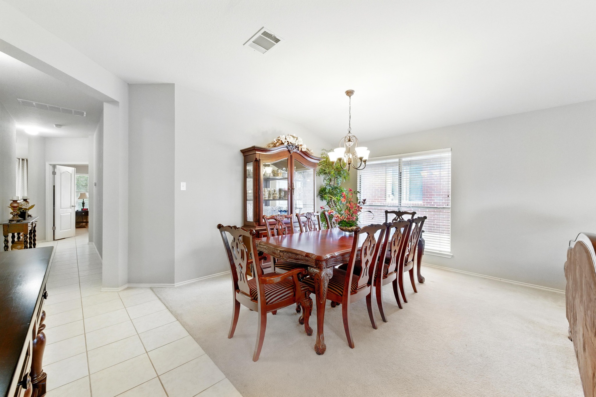 9602 Tea Rose Trail Austin, TX 78748 - Photo 5 of 27 Dining area featuring light colored carpet, healthy amount of natural light, light tile patterned floors, and a chandelier