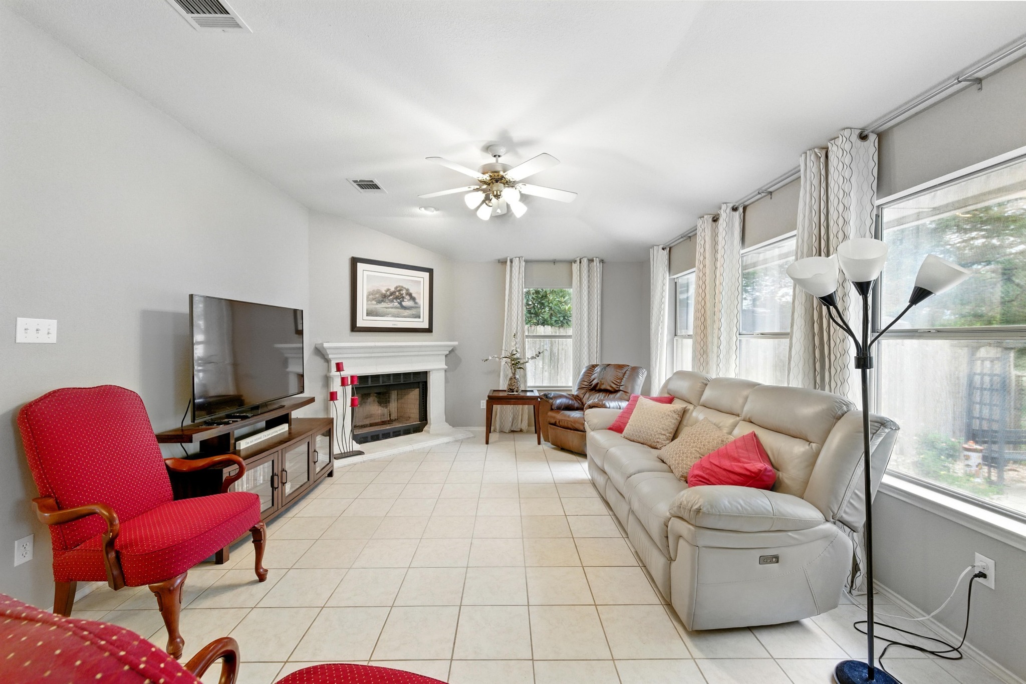 9602 Tea Rose Trail Austin, TX 78748 - Photo 7 of 27 Living room featuring ceiling fan, a fireplace with raised hearth, light tile patterned floors, and vaulted ceiling