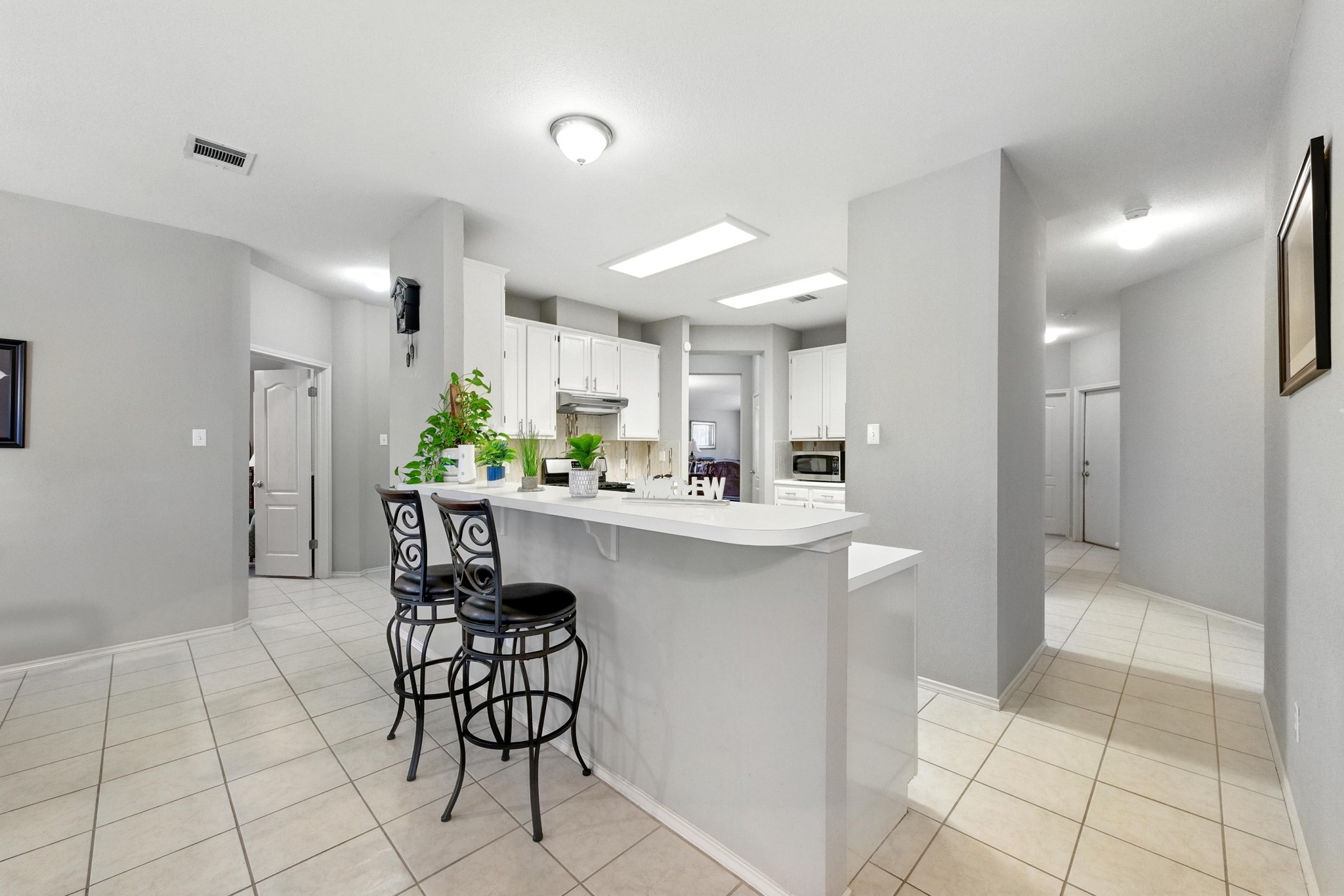 9602 Tea Rose Trail Austin, TX 78748 - Photo 10 of 27 Kitchen with a kitchen breakfast bar, light countertops, white cabinets, and light tile patterned floors