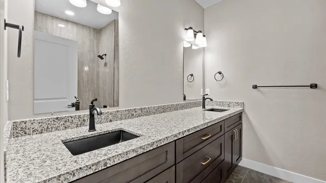 a bathroom with a granite countertop sink a mirror and shower
