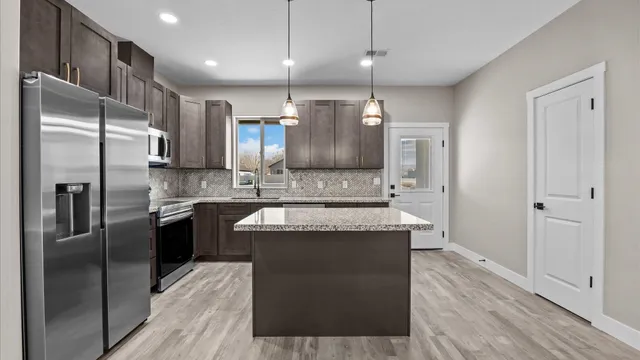 a kitchen with stainless steel appliances granite countertop a refrigerator a sink and a stove