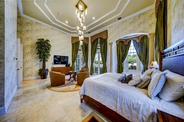 a bedroom with a large bed a chandelier and large window