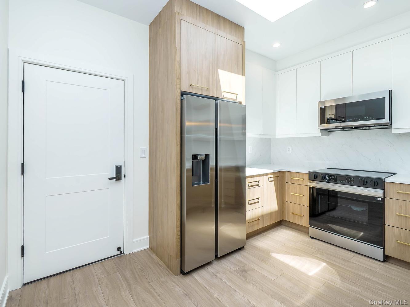 24 Lumber Road, Unit 2 Roslyn, NY 11576 - Photo 2 of 25 a kitchen with stainless steel appliances granite countertop a refrigerator and a stove top oven