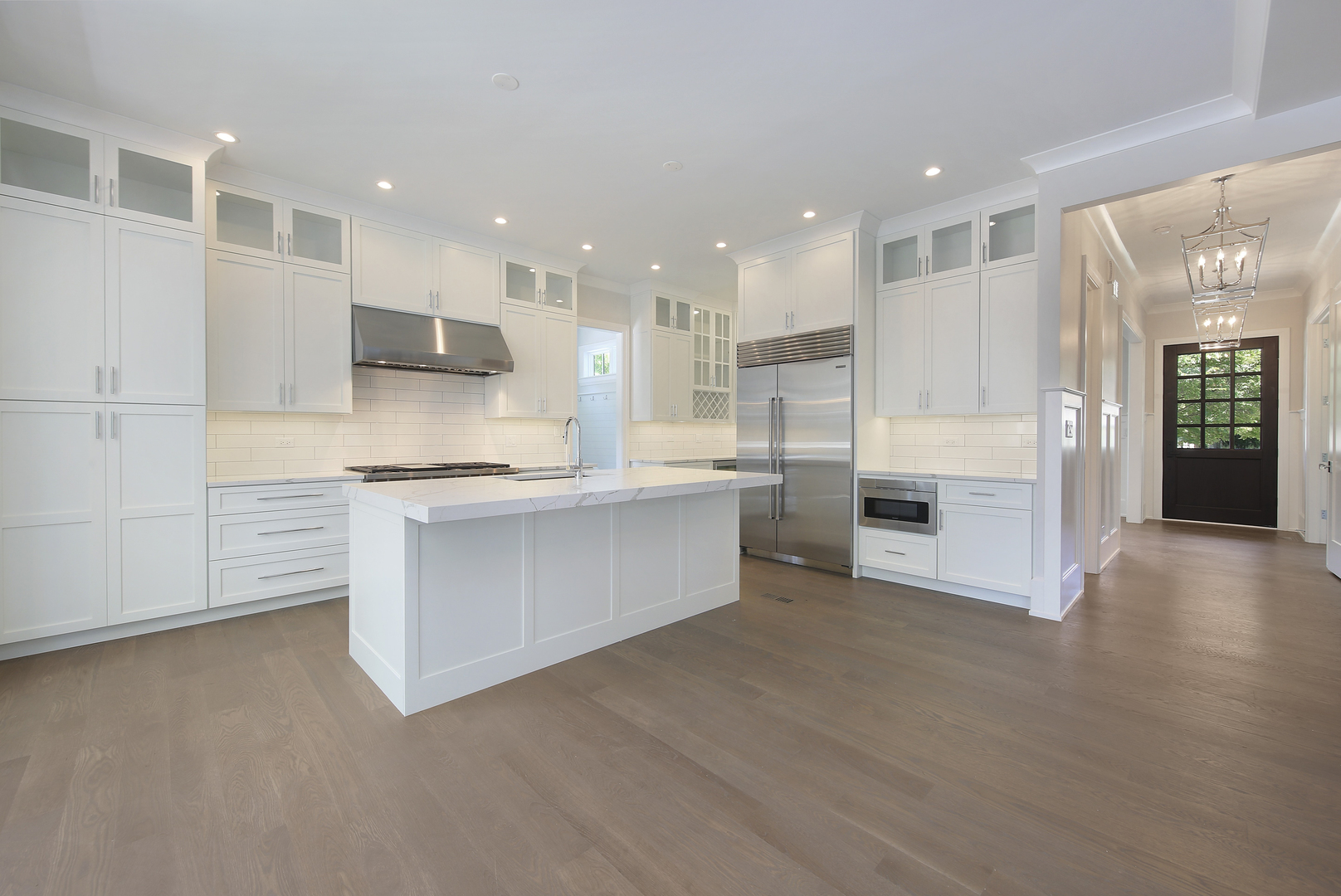 408 The Lane Hinsdale, IL 60521 - Photo 11 of 33 a large white kitchen with kitchen island a stove a sink a refrigerator and white cabinets with wooden floor