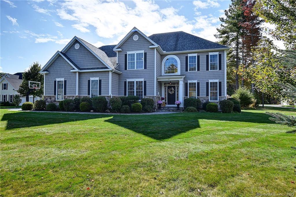 a front view of a house with a garden and trees