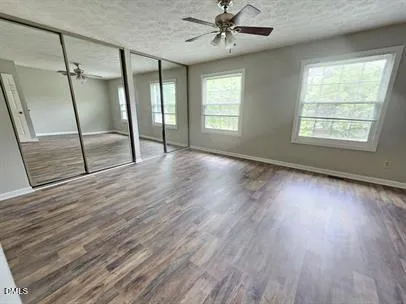 a view of an empty room with wooden floor and window