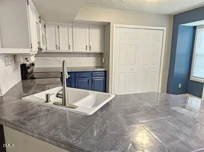 a kitchen with kitchen island granite countertop a sink a stove and cabinets