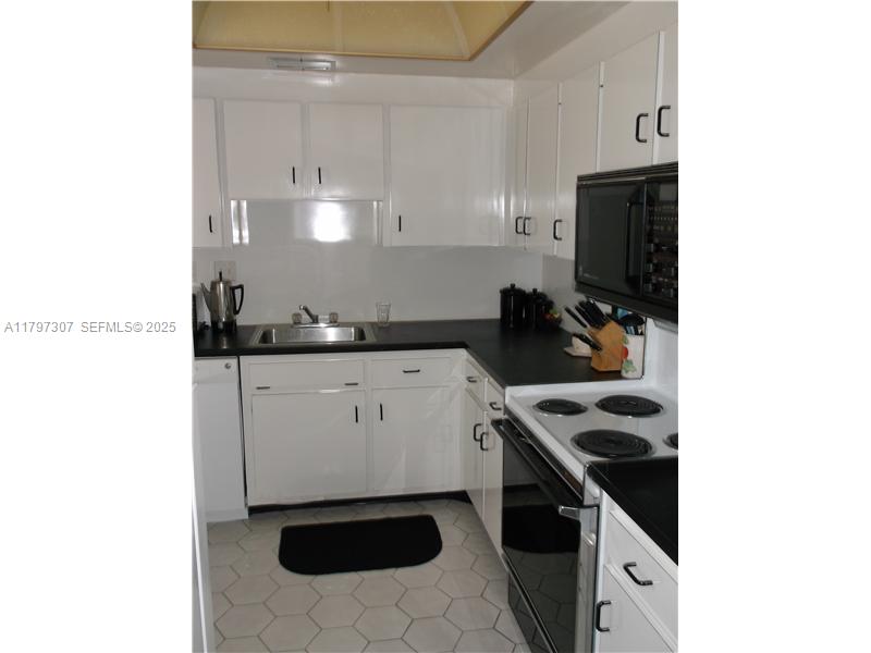 450 Golden Isles Drive, Unit 2H Hallandale Beach, FL 33009 - Photo 10 of 24 a kitchen with a sink and cabinets