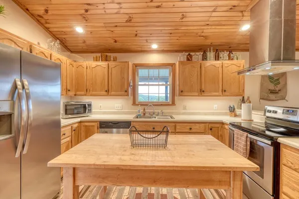 a large white kitchen with a stove a sink a refrigerator and cabinets