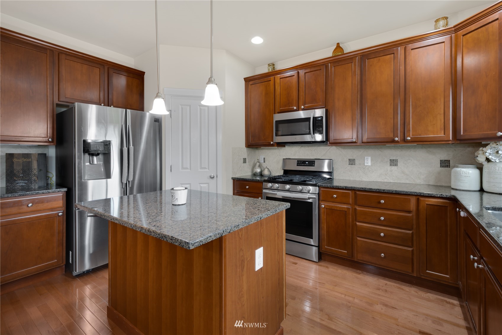 3712 224th Street Southeast Bothell, WA 98021 - Photo 8 of 24 a kitchen with stainless steel appliances granite countertop a refrigerator a stove a sink a microwave and wooden cabinets