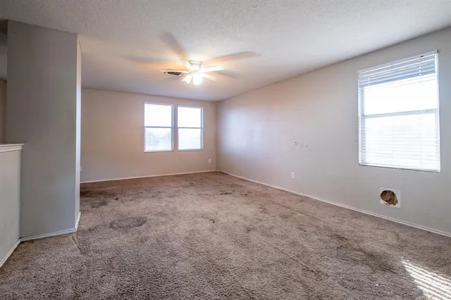 an empty room with windows and fan