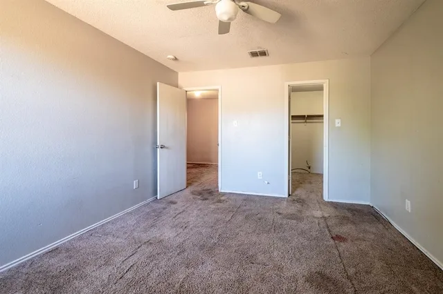 an empty room with closet and a chandelier fan
