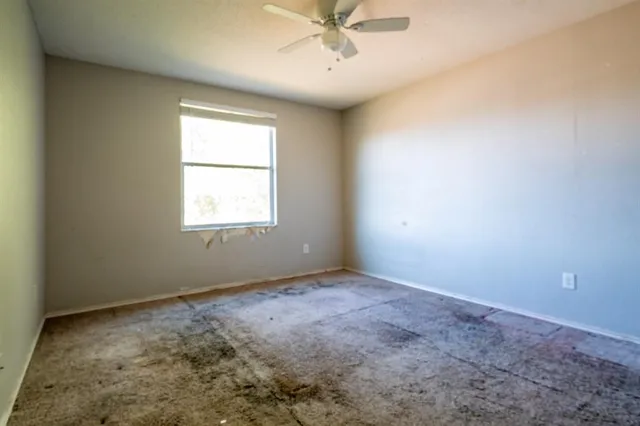 an empty room with a window and a fan