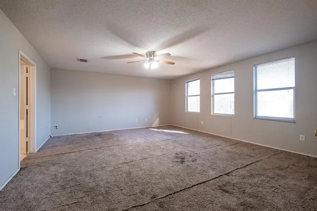 an empty room with windows and ceiling fan