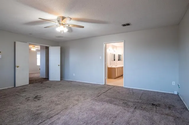 a view of an empty room with a chandelier fan