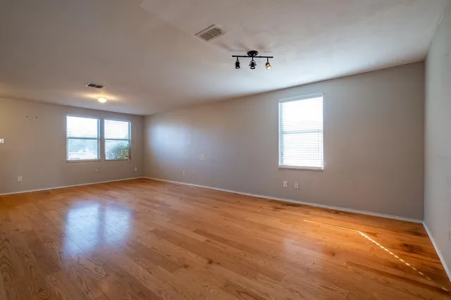 an empty room with wooden floor and windows