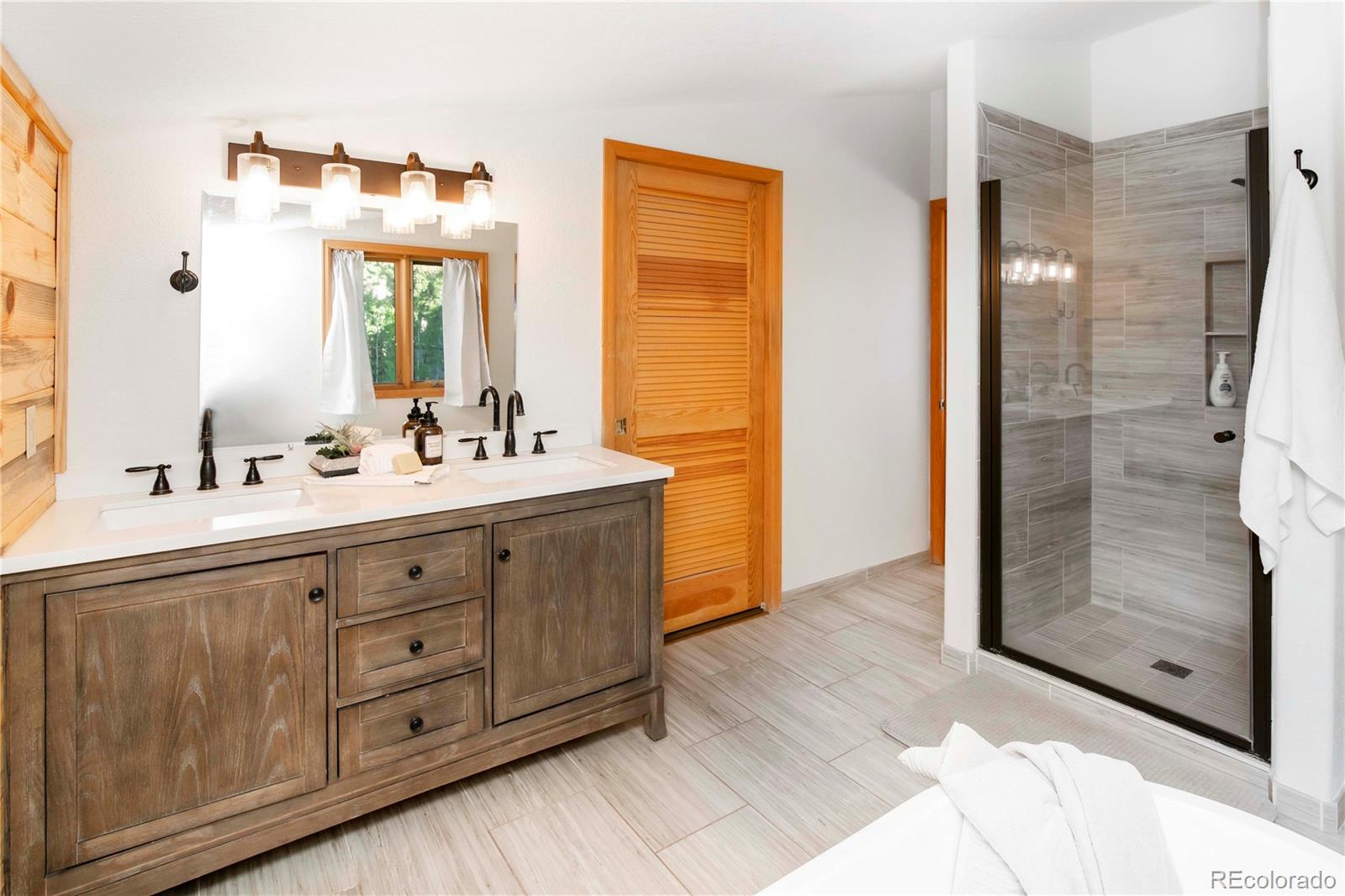13416 Kuehster Road Littleton, CO 80127 - Photo 34 of 50 a bathroom with a double vanity sink a mirror and a shower