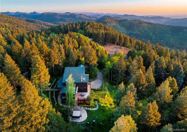 a view of a house with a lush green forest