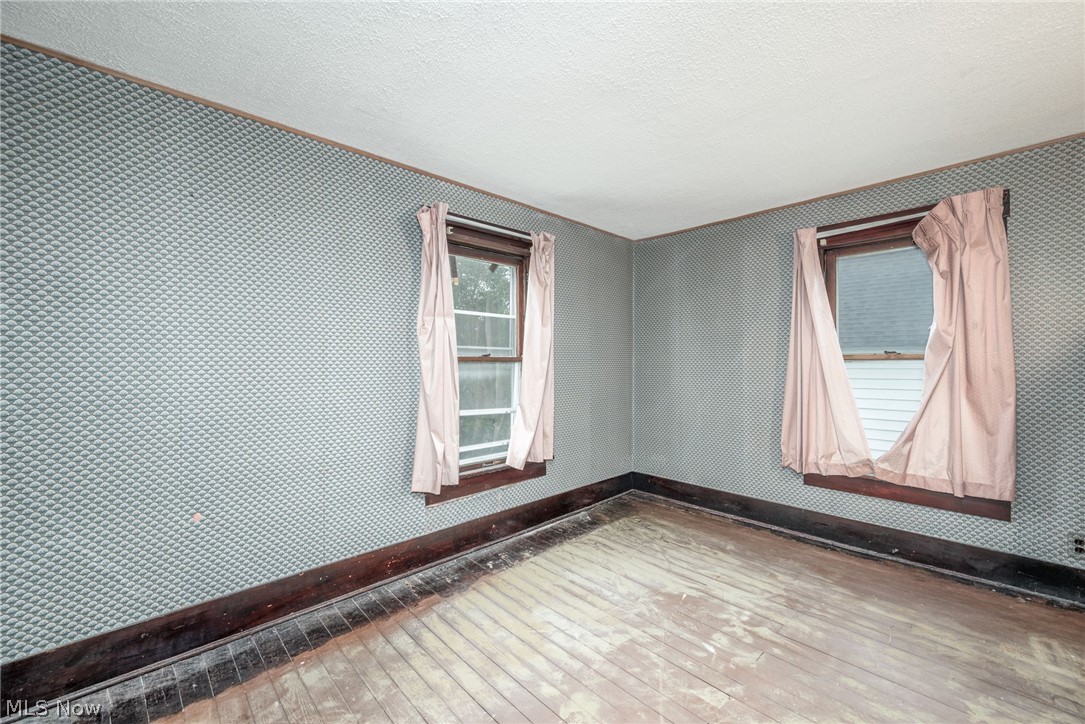 267 West Riddle Avenue Ravenna, OH 44266 - Photo 13 of 47 Patterned wallpaper, two windows, wood-finish flooring, dark wood trim, and a white ceiling
