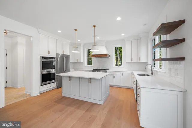 a kitchen with kitchen island a counter top space a sink stainless steel appliances and cabinets