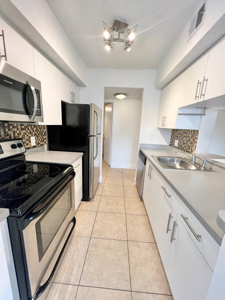 5612 Rock Island Road, Unit 141 Tamarac, FL 33319 - Photo 3 of 22 a kitchen with stainless steel appliances granite countertop a stove a sink and a microwave