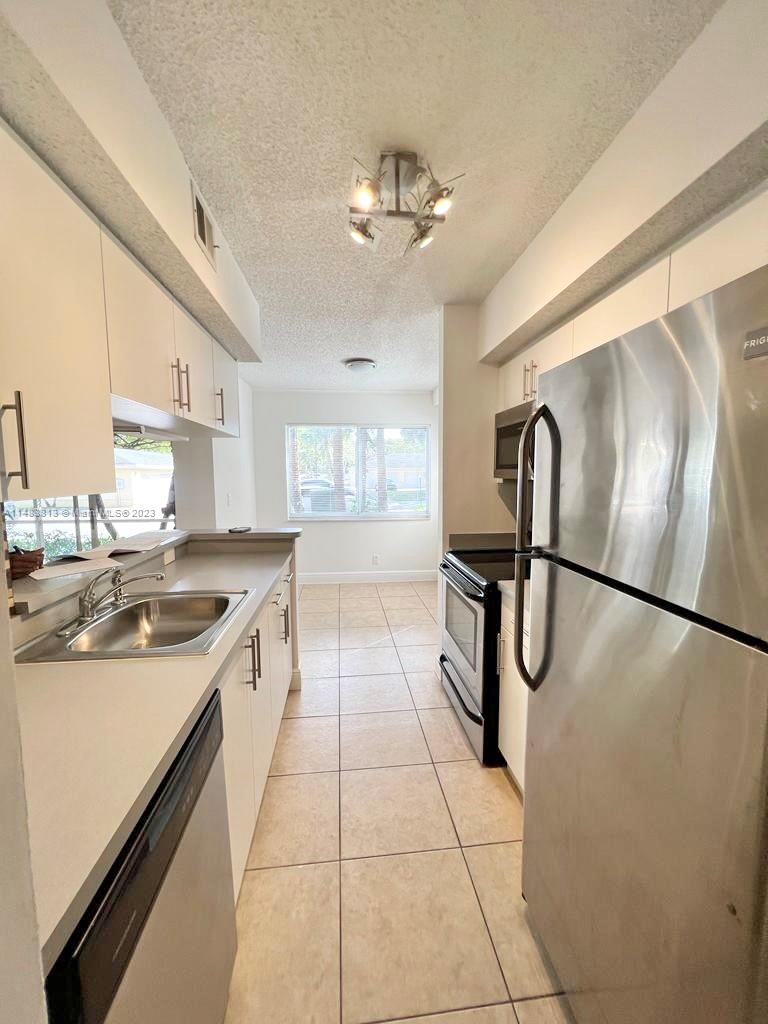 5612 Rock Island Road, Unit 141 Tamarac, FL 33319 - Photo 4 of 22 a kitchen with stainless steel appliances granite countertop a sink a stove a refrigerator cabinets and dining table with a large window
